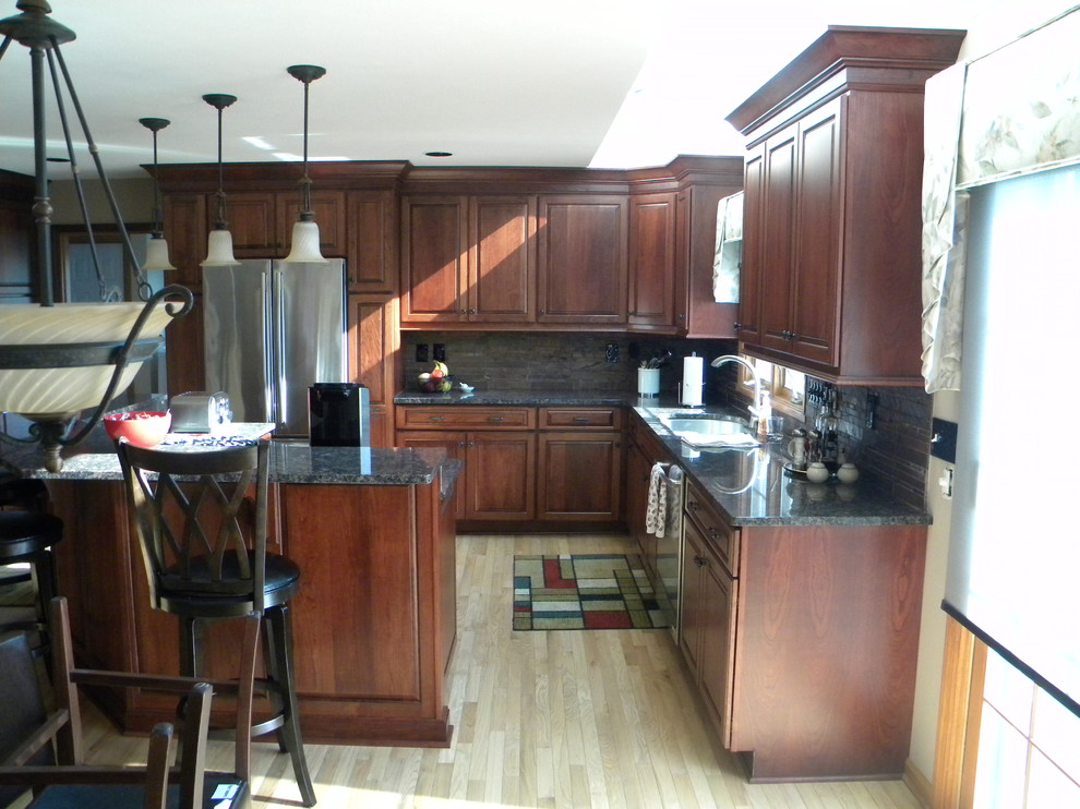 Mid-sized transitional u-shaped light wood floor eat-in kitchen photo with an undermount sink, raised-panel cabinets, medium tone wood cabinets, granite countertops, multicolored backsplash, stone tile backsplash, stainless steel appliances and an island