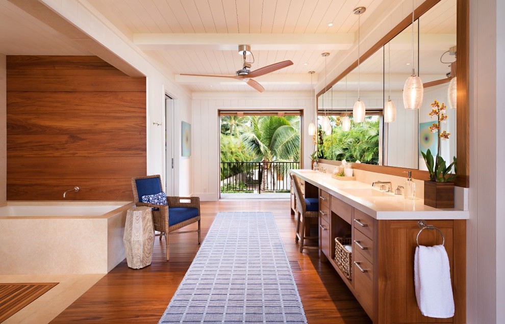 Design ideas for a large tropical master bathroom in Hawaii with flat-panel cabinets, medium wood cabinets, an undermount tub, white walls, an integrated sink, engineered quartz benchtops, dark hardwood floors, an alcove shower, white tile, stone slab and brown floor.