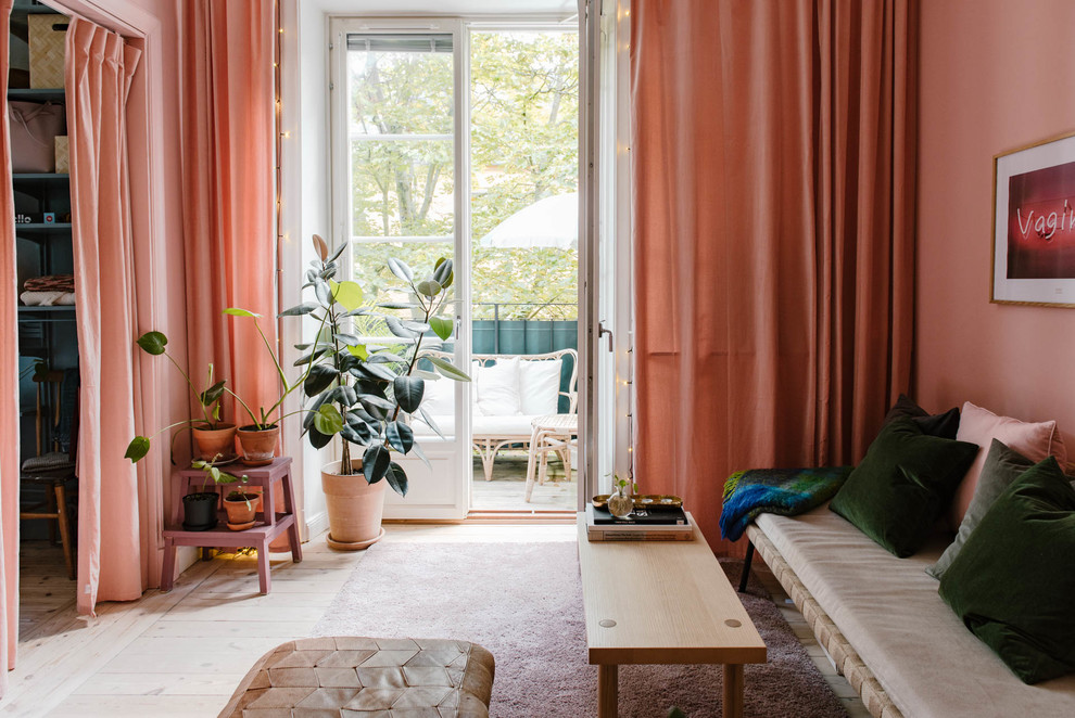 Photo of a small scandinavian living room in Stockholm with pink walls, light hardwood floors and beige floor.