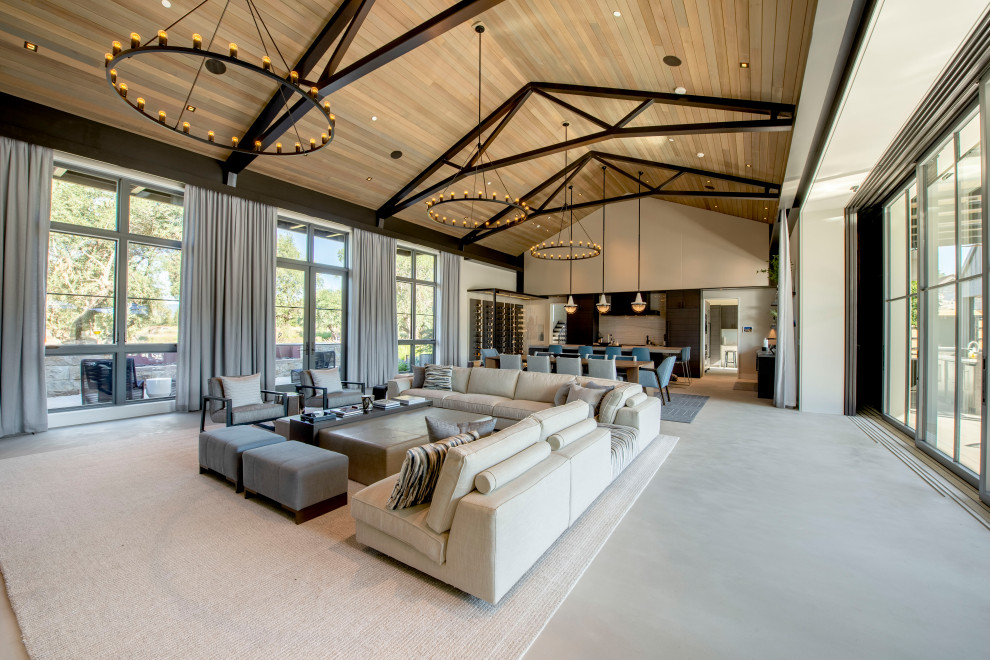 This is an example of a large country open concept living room in San Francisco with concrete floors, grey floor, white walls and vaulted.