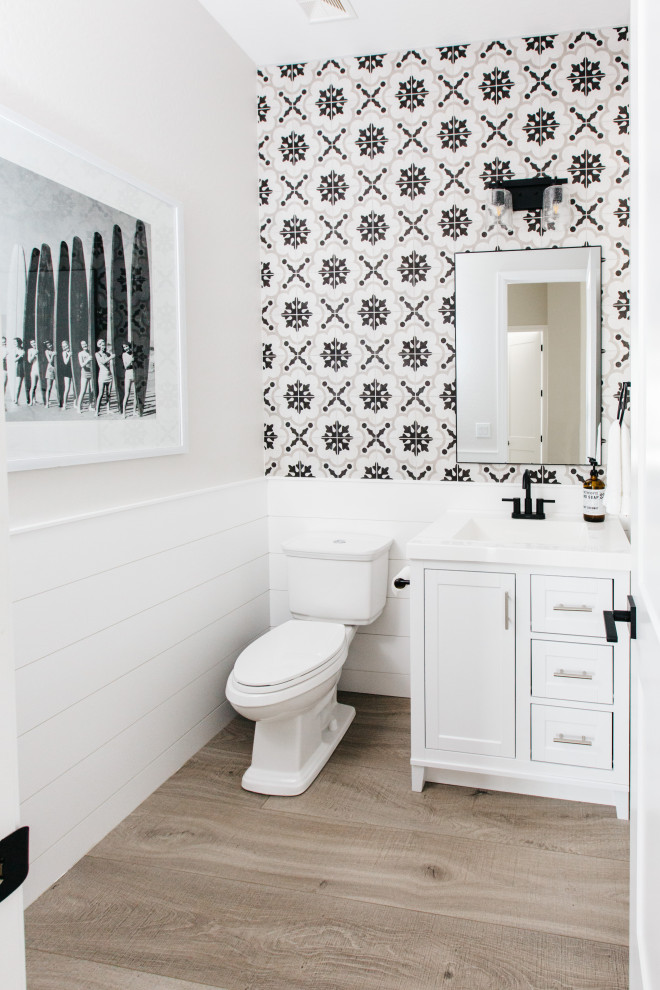 Inspiration for a transitional powder room in Phoenix with shaker cabinets, white cabinets, a two-piece toilet, multi-coloured tile, grey walls, medium hardwood floors, brown floor and white benchtops.