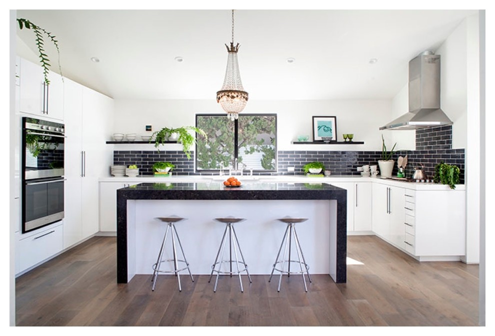 Design ideas for a mid-sized modern u-shaped eat-in kitchen in Orange County with an undermount sink, flat-panel cabinets, white cabinets, solid surface benchtops, black splashback, subway tile splashback, stainless steel appliances, dark hardwood floors, with island and brown floor.