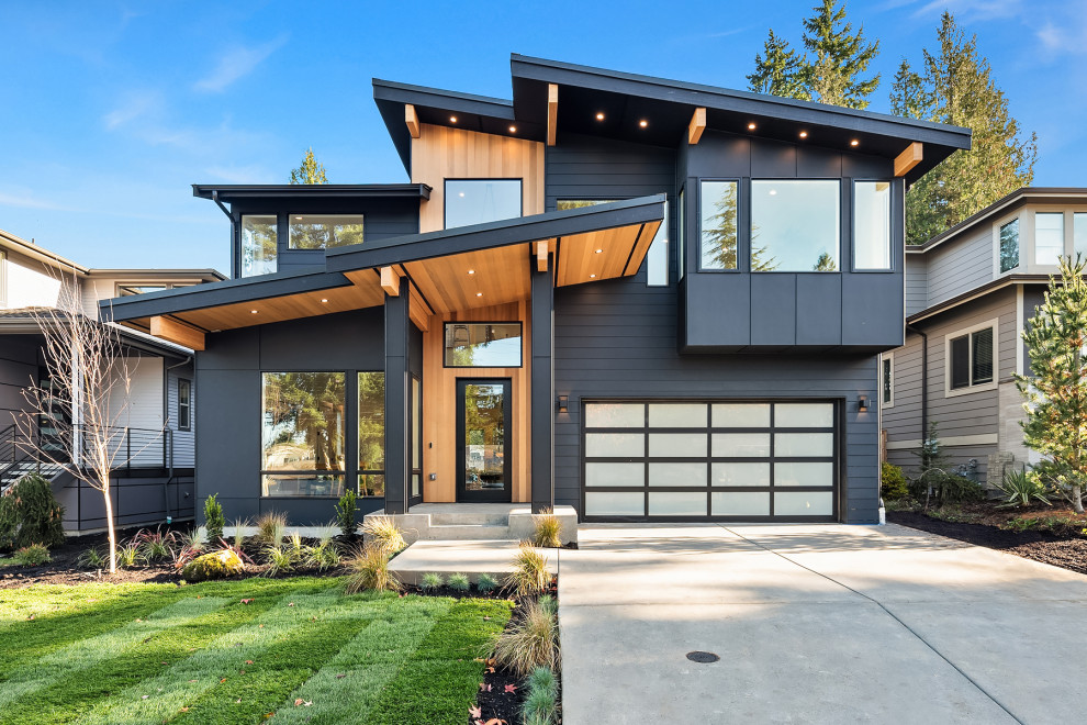 Mid-sized contemporary two-storey black house exterior in Seattle with concrete fiberboard siding, a shed roof, a black roof and clapboard siding.