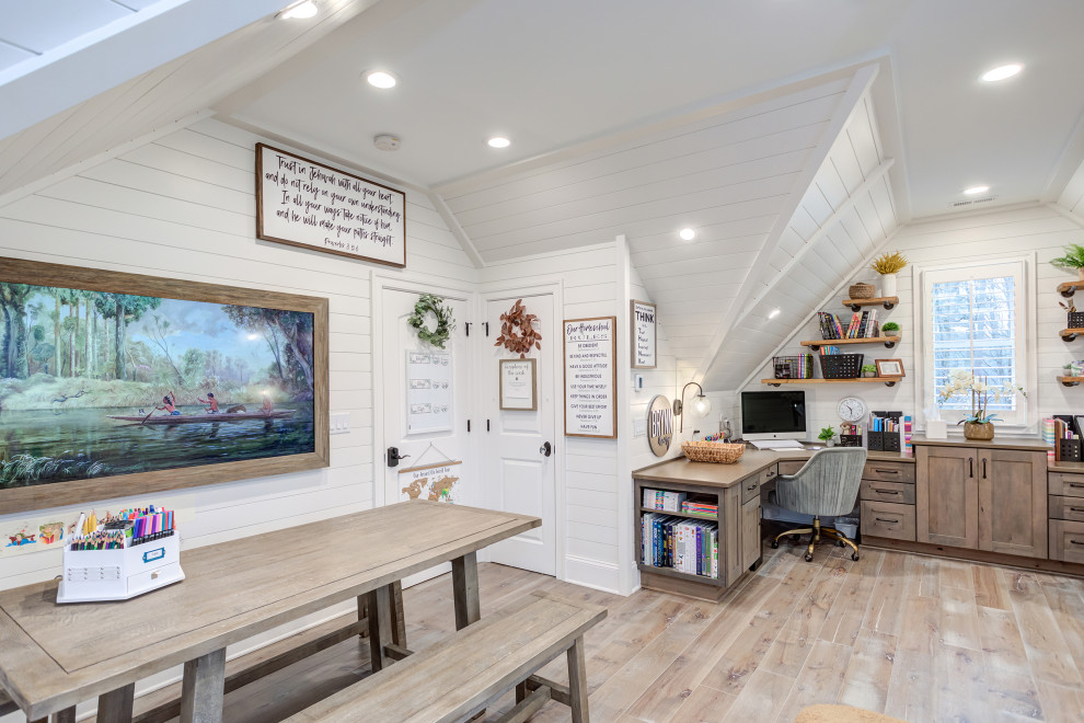 Cette image montre une grande chambre neutre craftsman avec un bureau, un mur blanc, un sol en bois brun, un sol gris et du lambris de bois.