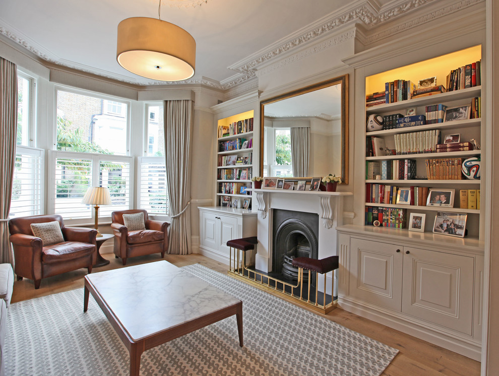 Design ideas for a traditional living room in London with a library, light hardwood floors, a standard fireplace and no tv.