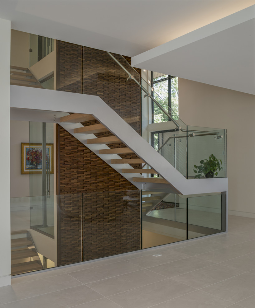 Photo of a large modern glass l-shaped staircase in Other with glass risers and wood railing.