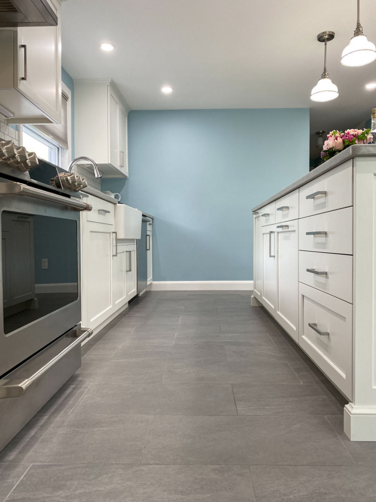 Eat-in kitchen - transitional porcelain tile and gray floor eat-in kitchen idea in Boston with a farmhouse sink, raised-panel cabinets, white cabinets, quartz countertops, white backsplash, ceramic backsplash, stainless steel appliances, an island and white countertops