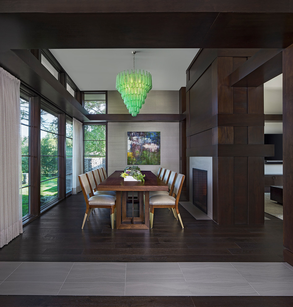 This is an example of a large contemporary open plan dining in Detroit with metallic walls, dark hardwood floors, a two-sided fireplace, a tile fireplace surround and brown floor.
