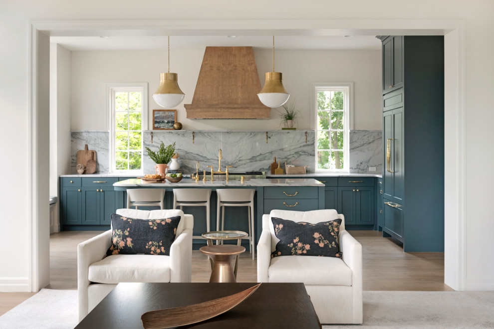 Inspiration for an expansive traditional open plan kitchen in Minneapolis with a farmhouse sink, recessed-panel cabinets, blue cabinets, grey splashback, panelled appliances, light hardwood floors, with island, white benchtop, quartzite benchtops and stone slab splashback.