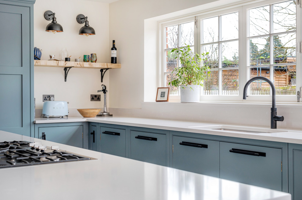 バークシャーにある高級な広いおしゃれなキッチン (シェーカースタイル扉のキャビネット、青いキャビネット、人工大理石カウンター) の写真