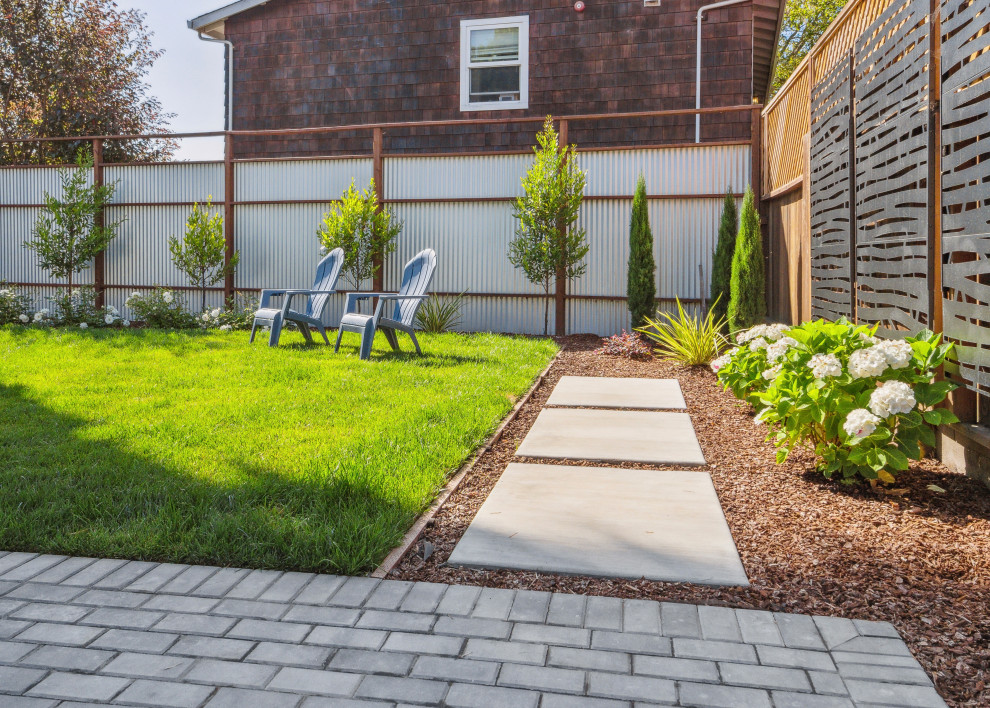This is an example of a small modern back partial sun garden in San Francisco with a pathway, brick paving and a metal fence.