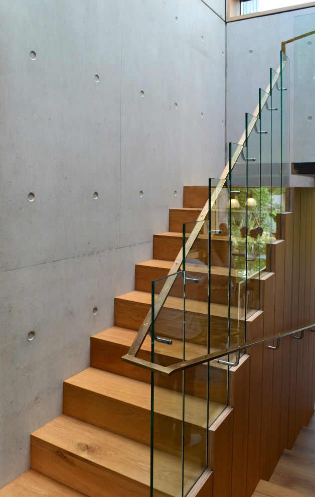 Photo of a mid-sized modern wood u-shaped staircase in London with wood risers and mixed railing.