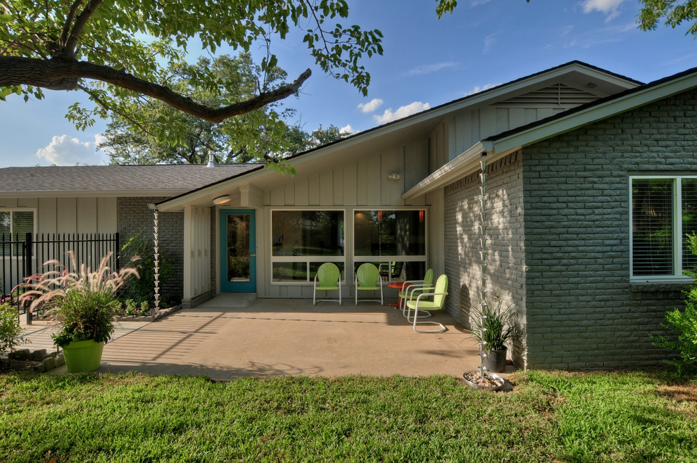 Inspiration for a large midcentury backyard verandah in Dallas with concrete slab and a roof extension.