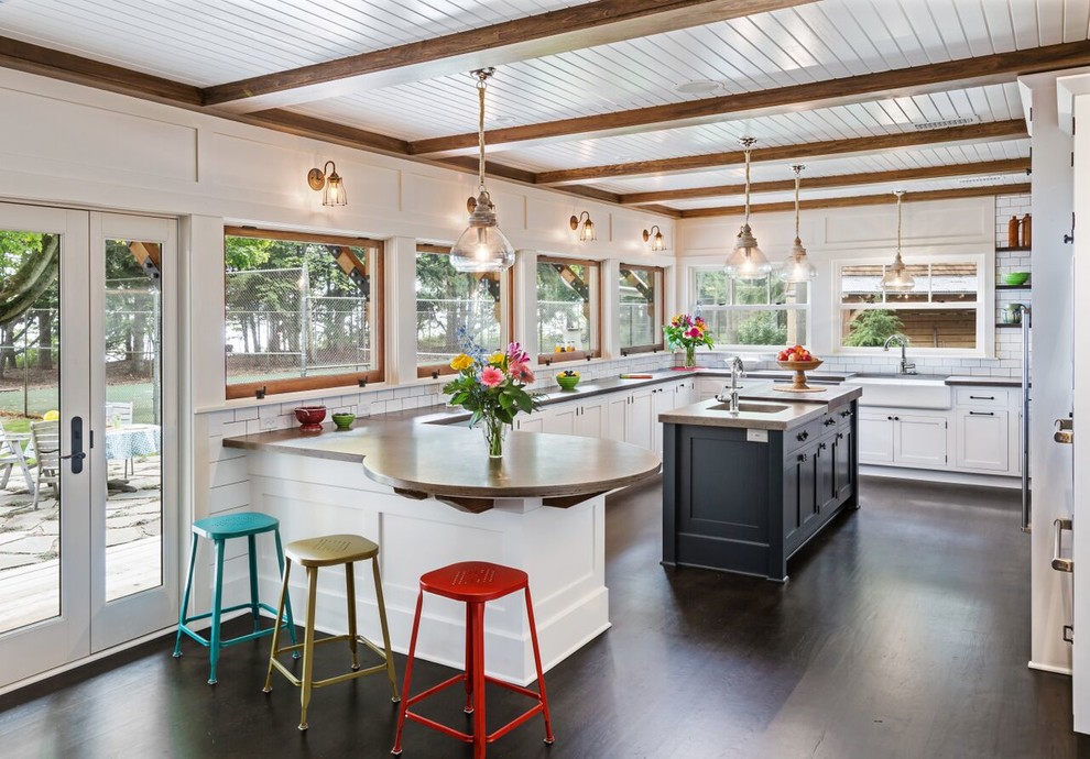 Inspiration for a transitional u-shaped eat-in kitchen in Milwaukee with a farmhouse sink, white cabinets, white splashback, subway tile splashback, dark hardwood floors, with island, concrete benchtops, stainless steel appliances and shaker cabinets.