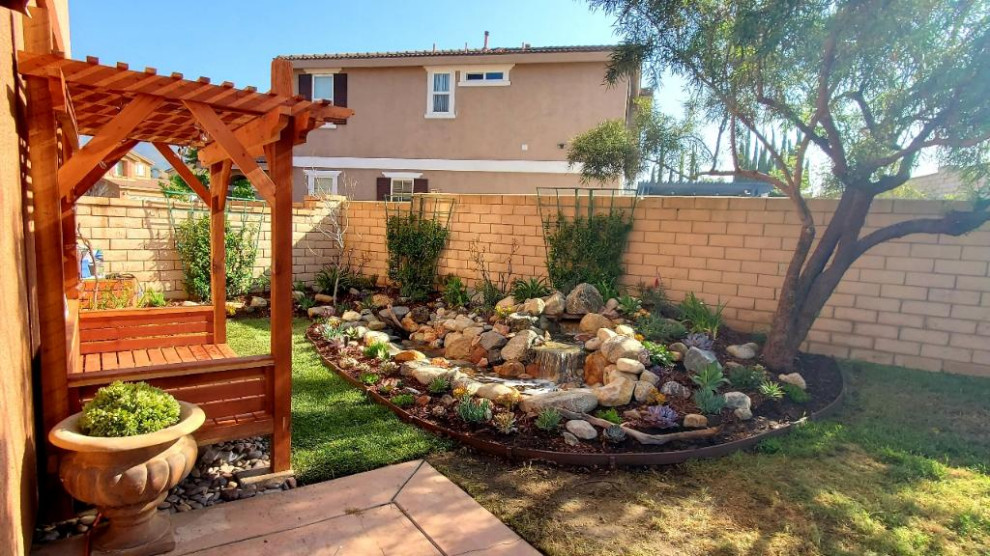 Mid-sized side yard partial sun xeriscape in San Diego with with waterfall and mulch for summer.