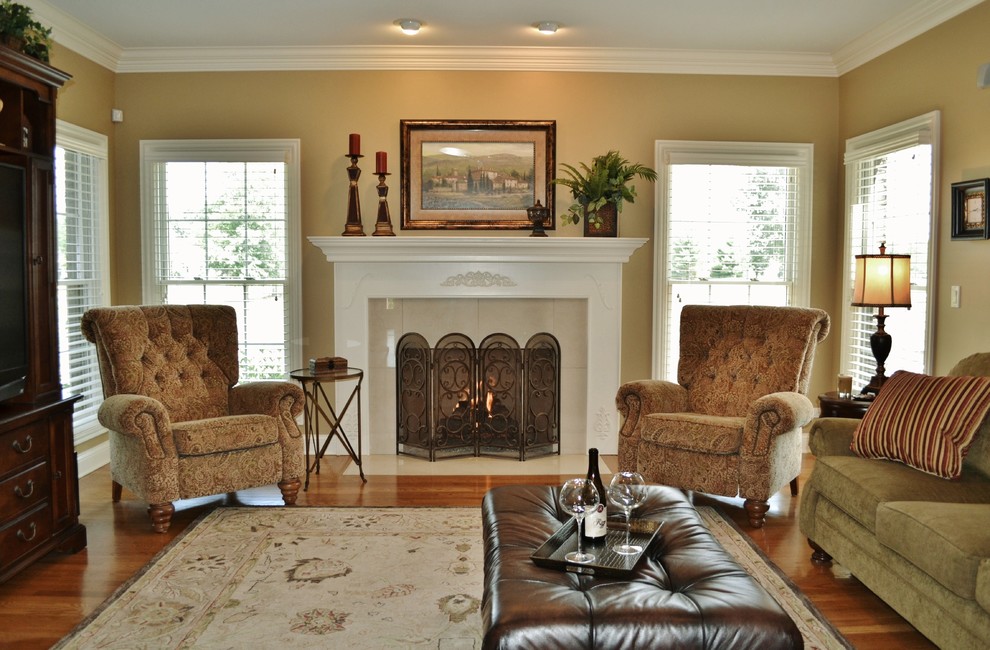 This is an example of a traditional family room in Chicago with beige walls, medium hardwood floors and a standard fireplace.