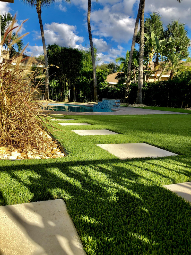 Medium sized classic back kidney-shaped swimming pool in Miami with with pool landscaping and concrete paving.