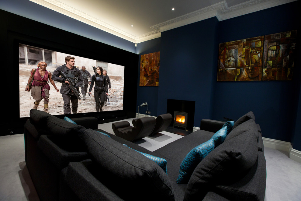 This is an example of a mid-sized contemporary enclosed home theatre in London with blue walls, carpet and a projector screen.