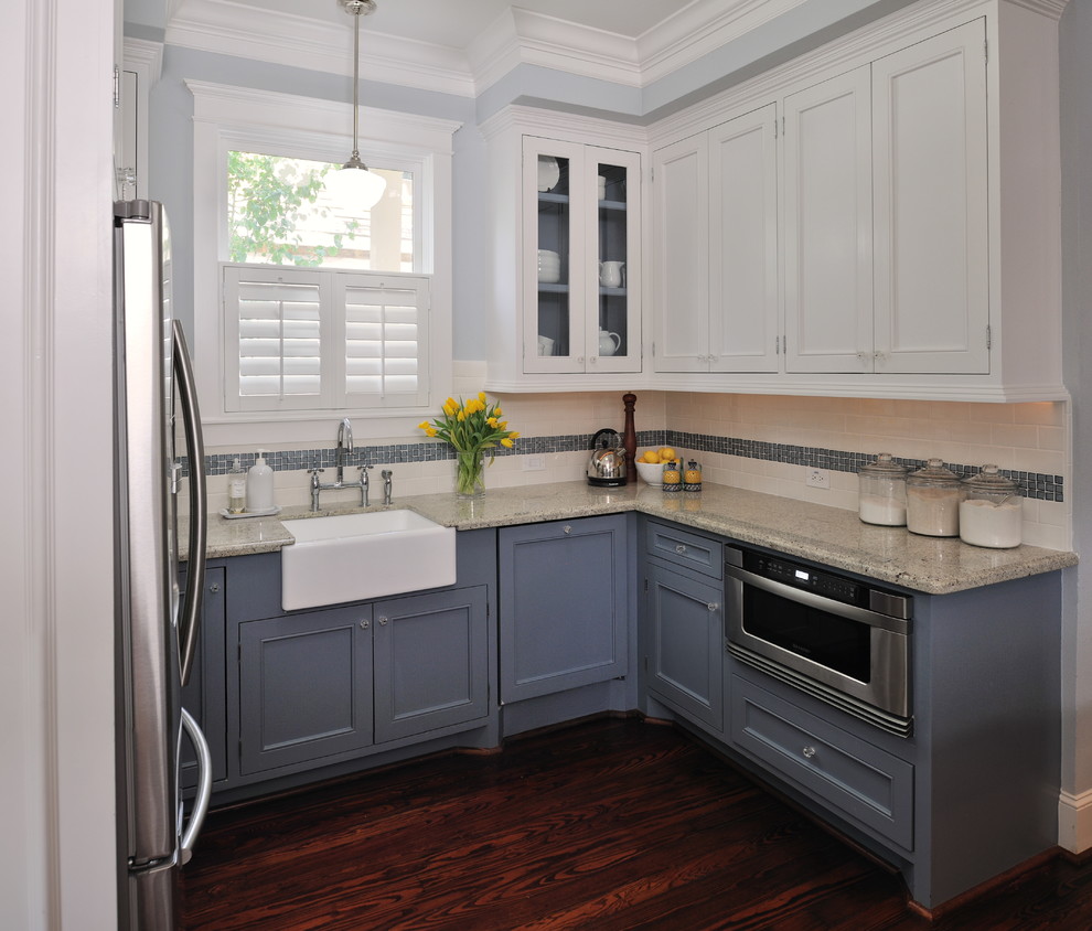 This is an example of a traditional kitchen in Houston with a farmhouse sink, blue cabinets, granite benchtops, white splashback, stainless steel appliances, subway tile splashback and recessed-panel cabinets.