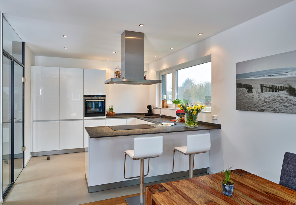 Design ideas for a mid-sized contemporary u-shaped eat-in kitchen in Other with an undermount sink, flat-panel cabinets, stainless steel cabinets, stainless steel appliances, a peninsula, white splashback, solid surface benchtops and linoleum floors.