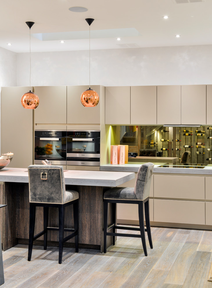 This is an example of a large contemporary u-shaped eat-in kitchen in London with flat-panel cabinets, concrete benchtops, mirror splashback, medium hardwood floors and with island.