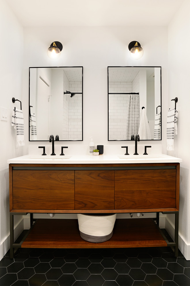 Inspiration for a mid-sized midcentury 3/4 bathroom in Dallas with flat-panel cabinets, medium wood cabinets, an alcove tub, a shower/bathtub combo, a two-piece toilet, white tile, ceramic tile, white walls, porcelain floors, an undermount sink, engineered quartz benchtops, black floor, a shower curtain, white benchtops, a double vanity and a freestanding vanity.