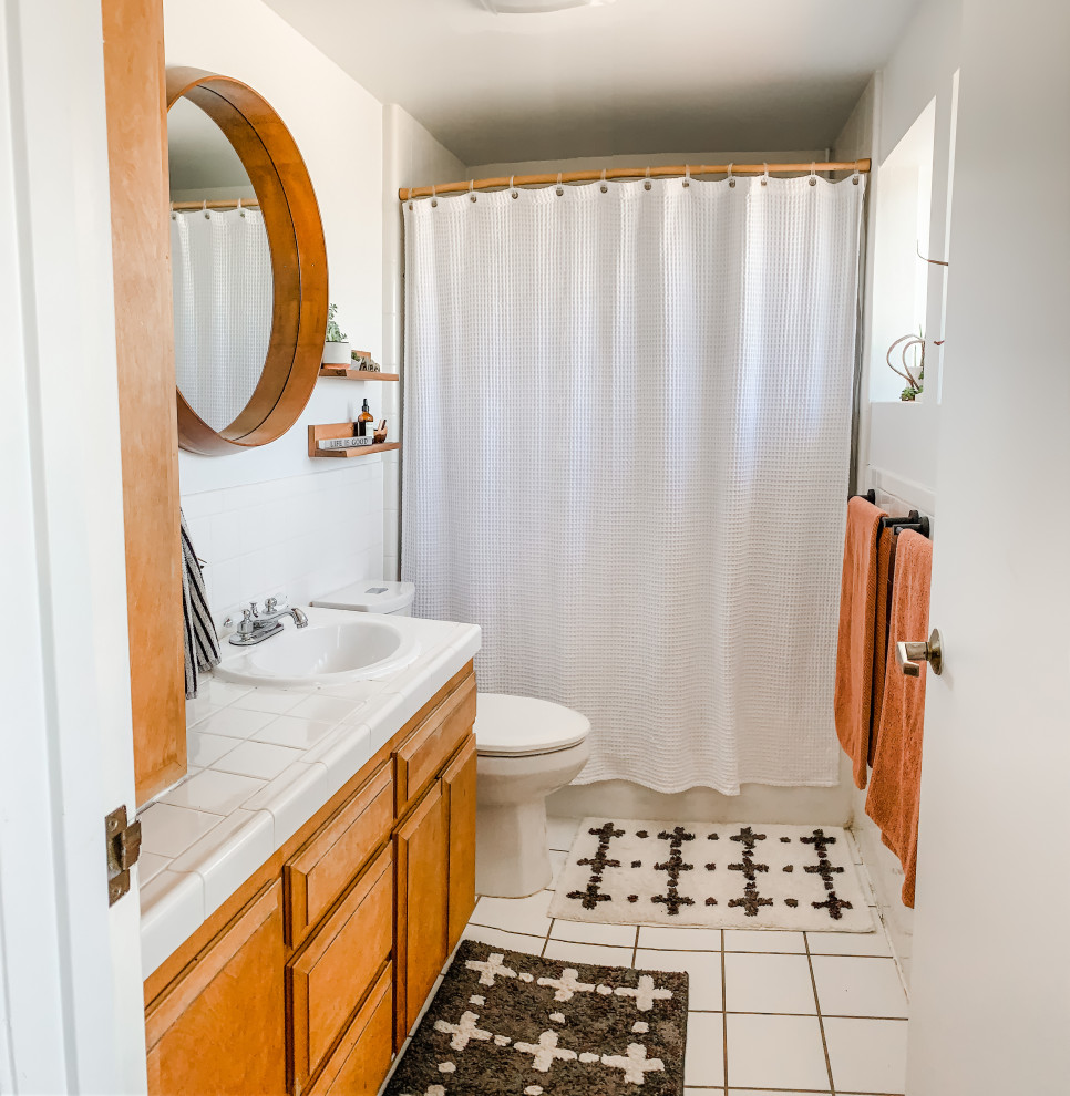 Photo of a small arts and crafts kids bathroom in Los Angeles with a drop-in tub, a two-piece toilet, yellow tile, ceramic tile, white walls, ceramic floors, a drop-in sink, tile benchtops, white floor, a shower curtain, white benchtops, a single vanity and a built-in vanity.