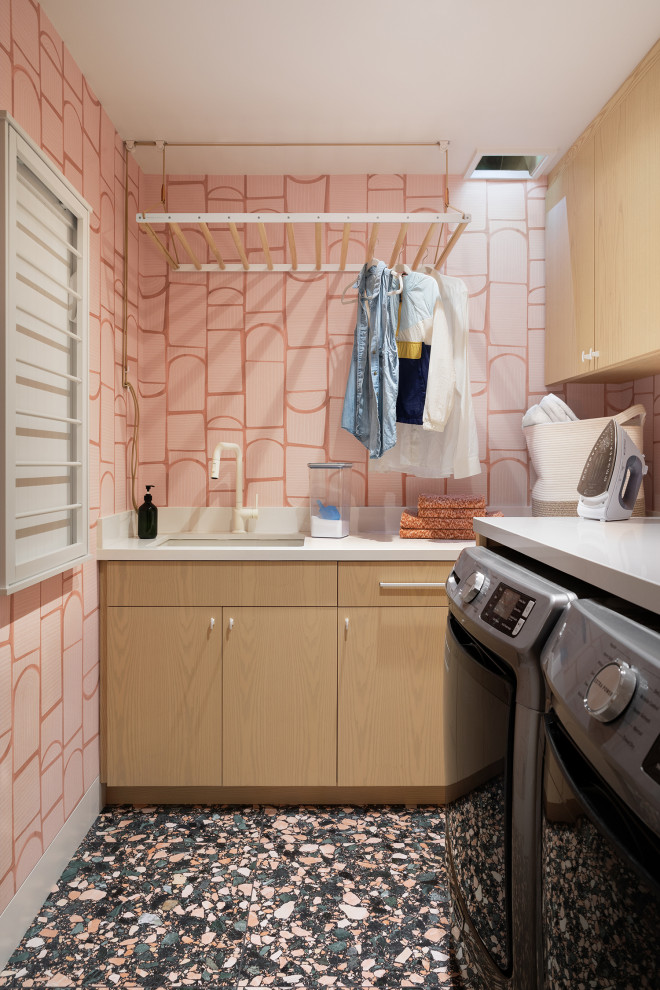 Inspiration for a contemporary l-shaped multicolored floor and wallpaper dedicated laundry room remodel in San Francisco with an undermount sink, flat-panel cabinets, light wood cabinets, quartz countertops, pink walls, a side-by-side washer/dryer and white countertops