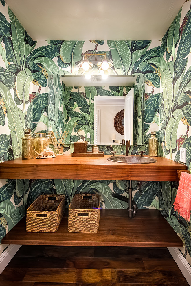 Inspiration for a large tropical 3/4 bathroom in San Diego with a drop-in sink, medium wood cabinets, wood benchtops, a one-piece toilet, green walls, medium hardwood floors, open cabinets and brown benchtops.