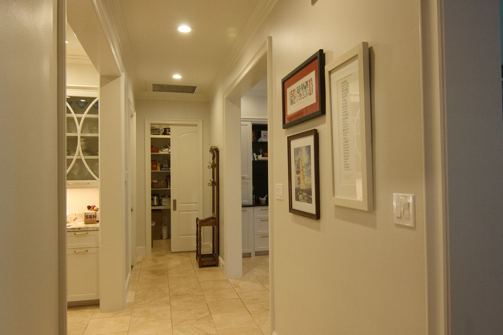 Photo of a mid-sized transitional hallway in Houston with white walls and travertine floors.