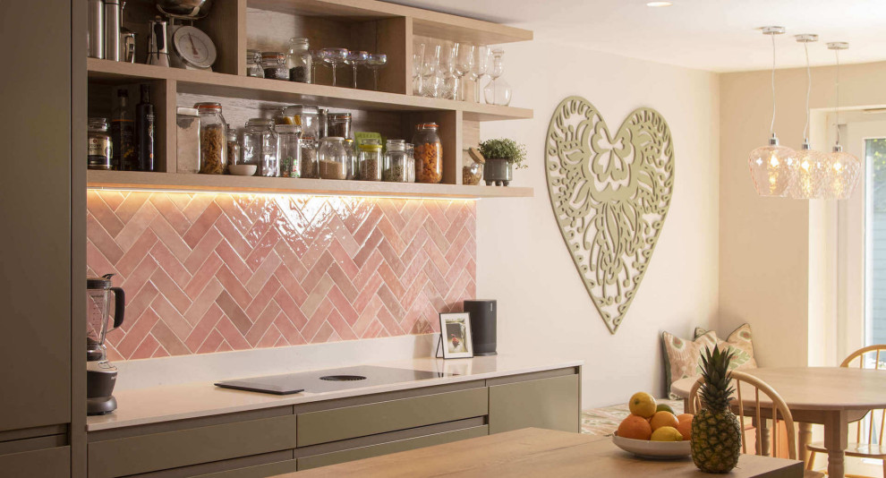 This is an example of a medium sized contemporary l-shaped kitchen/diner in Sussex with flat-panel cabinets, light wood cabinets, quartz worktops, pink splashback, terracotta splashback, an island and white worktops.