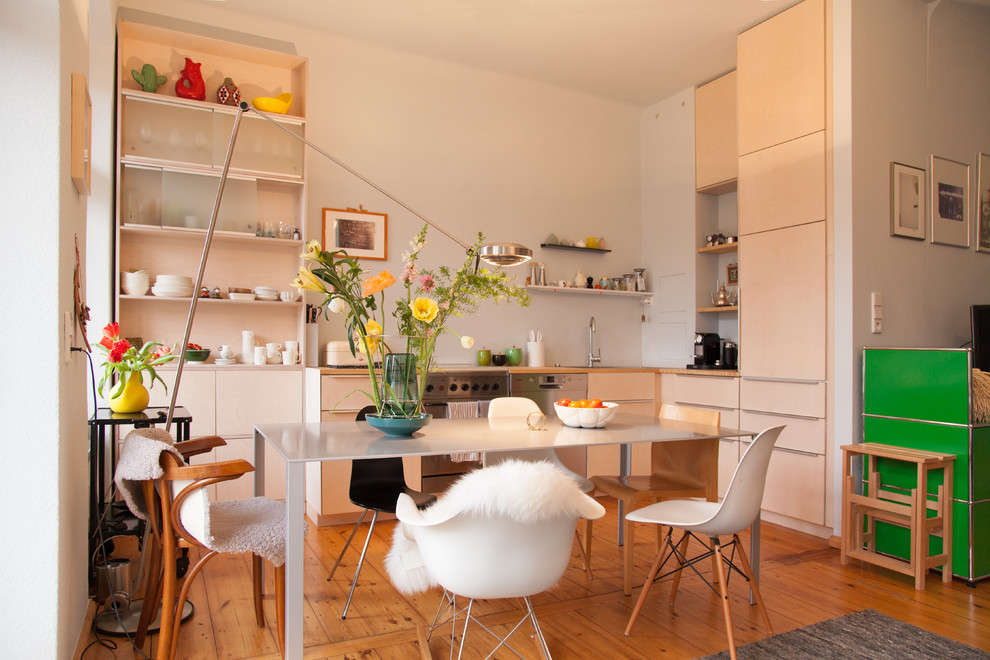Mid-sized scandinavian l-shaped eat-in kitchen in Berlin with flat-panel cabinets, beige cabinets, wood benchtops, blue splashback, no island, a drop-in sink, stainless steel appliances, light hardwood floors and brown floor.