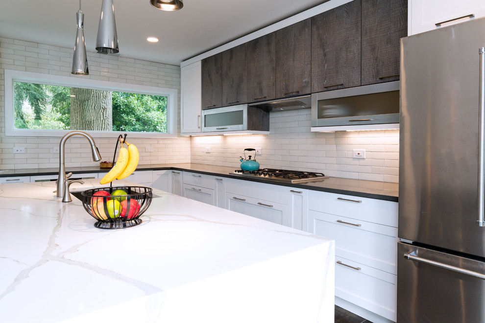 Mid-sized midcentury l-shaped eat-in kitchen in DC Metro with an undermount sink, shaker cabinets, white cabinets, solid surface benchtops, white splashback, subway tile splashback, stainless steel appliances and with island.