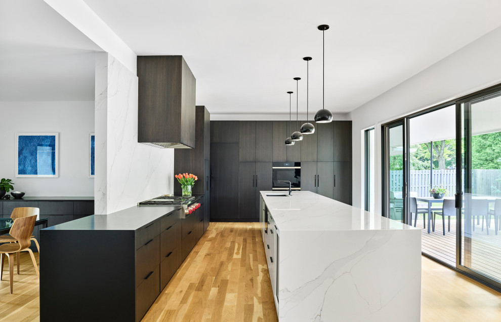 Immagine di una grande cucina minimalista con lavello sottopiano, ante lisce, ante in legno bruno, top in legno, paraspruzzi bianco, paraspruzzi in quarzo composito, parquet chiaro e top nero