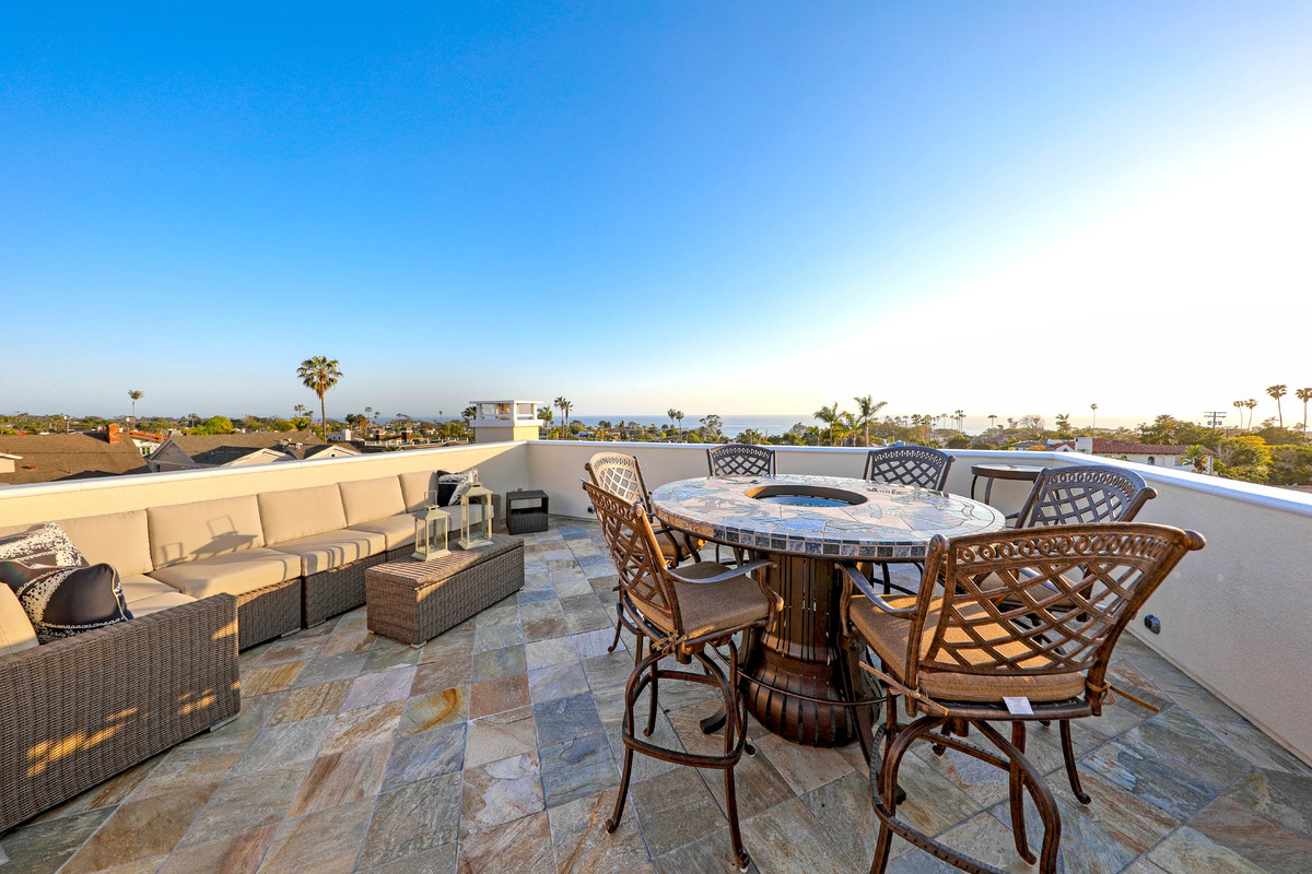 Example of a mid-sized transitional rooftop deck design in Orange County with a fire pit and no cover