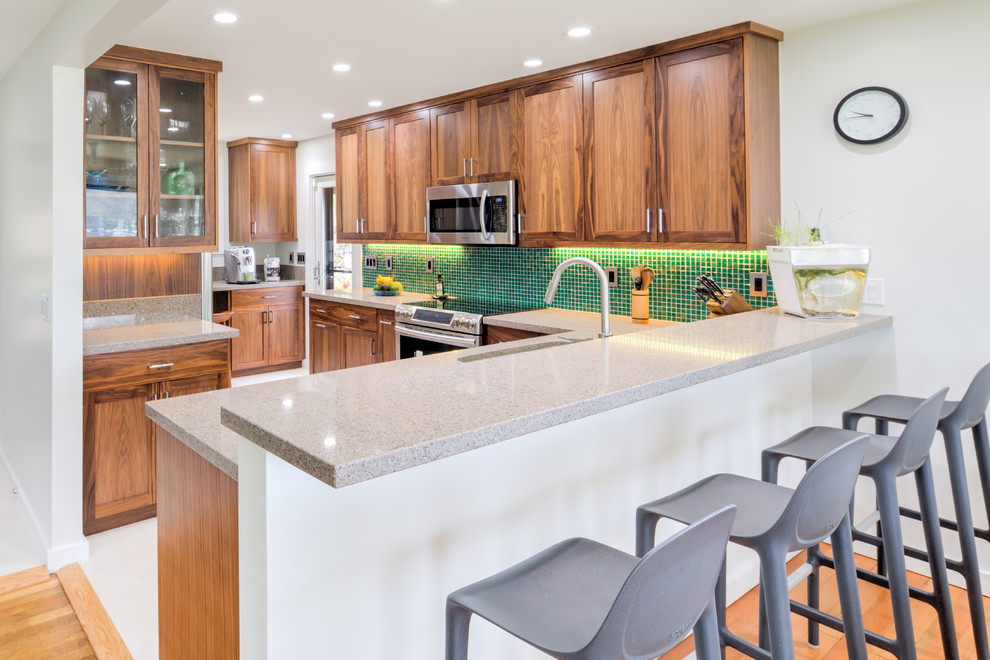 Inspiration for a mid-sized transitional l-shaped eat-in kitchen in Hawaii with medium wood cabinets, granite benchtops, green splashback, mosaic tile splashback, stainless steel appliances, porcelain floors, no island, an undermount sink and shaker cabinets.