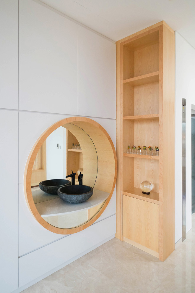 Inspiration for an asian bathroom in Singapore with open cabinets, light wood cabinets, white walls, a vessel sink and beige floor.
