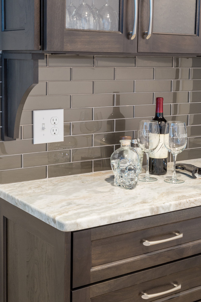 Inspiration for a small transitional single-wall home bar in Providence with recessed-panel cabinets, dark wood cabinets, quartzite benchtops, brown splashback, glass tile splashback and porcelain floors.