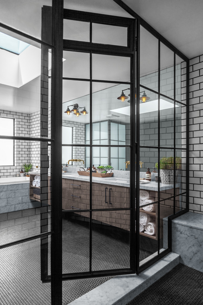 Inspiration for a large industrial master wet room bathroom in Los Angeles with raised-panel cabinets, light wood cabinets, a drop-in tub, a one-piece toilet, black and white tile, porcelain tile, black walls, a drop-in sink, marble benchtops, black floor, a hinged shower door, grey benchtops and ceramic floors.