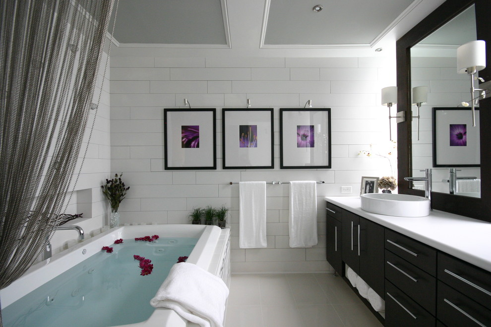This is an example of a mid-sized contemporary master bathroom in Charlotte with a vessel sink, flat-panel cabinets, dark wood cabinets, laminate benchtops, a drop-in tub, white tile, subway tile and light hardwood floors.