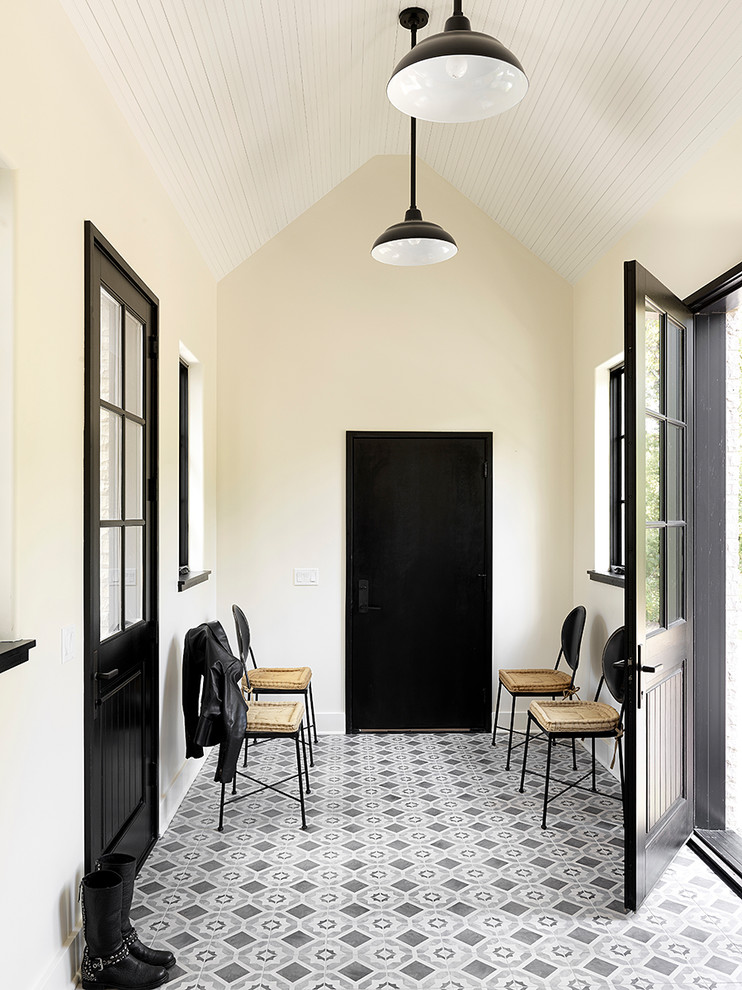 Photo of a scandinavian entry hall in Chicago with yellow walls, a single front door, a black front door and grey floor.