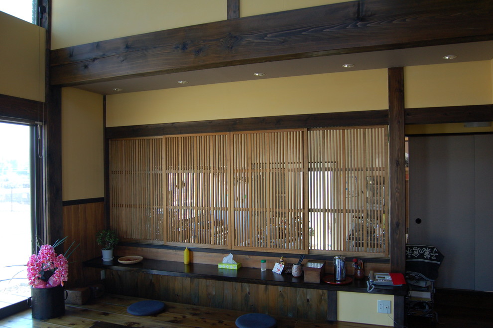 Asian dining room in Other with yellow walls, dark hardwood floors, no fireplace and brown floor.
