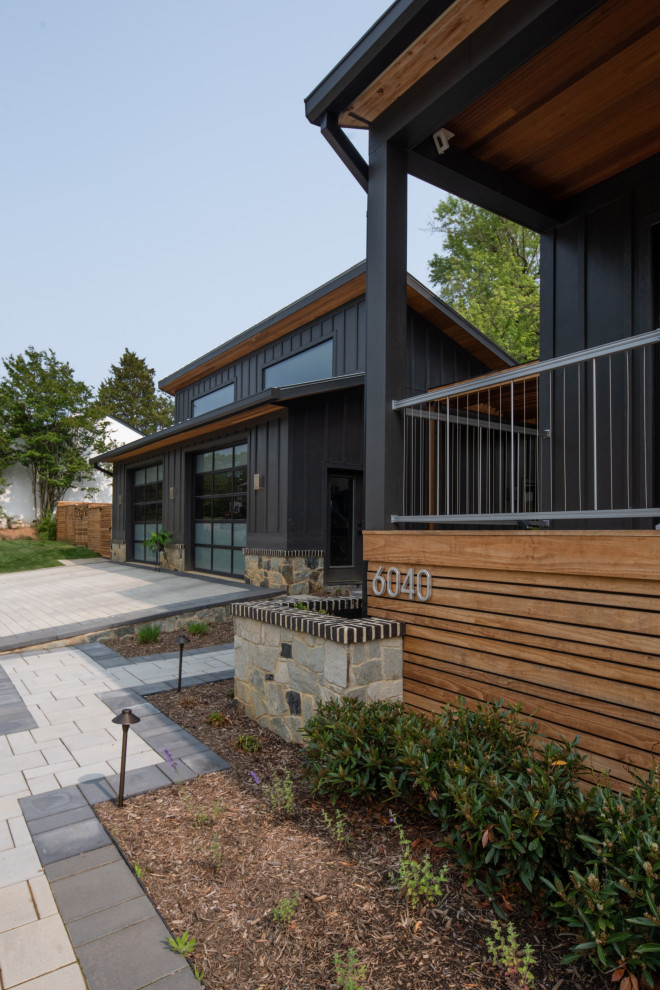 Photo of an expansive and black contemporary two floor detached house in DC Metro with wood cladding, a metal roof, a black roof and board and batten cladding.