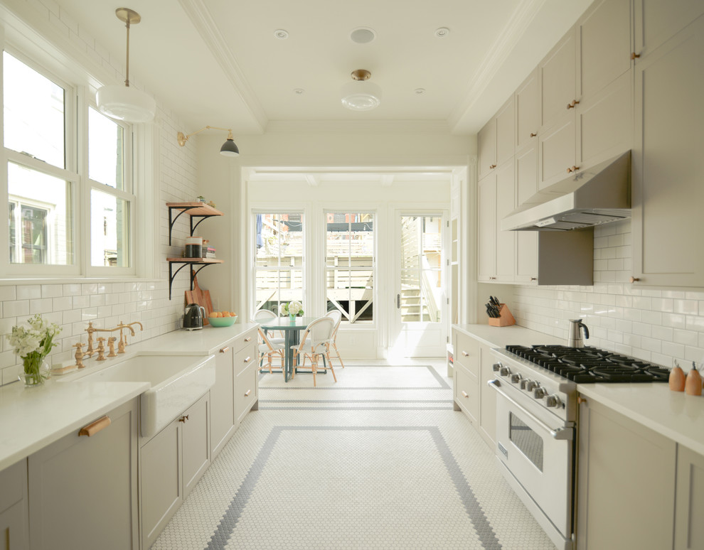 Photo of a mid-sized traditional galley eat-in kitchen in DC Metro with a farmhouse sink, recessed-panel cabinets, beige cabinets, quartz benchtops, white splashback, subway tile splashback, stainless steel appliances, porcelain floors, no island, white floor and white benchtop.