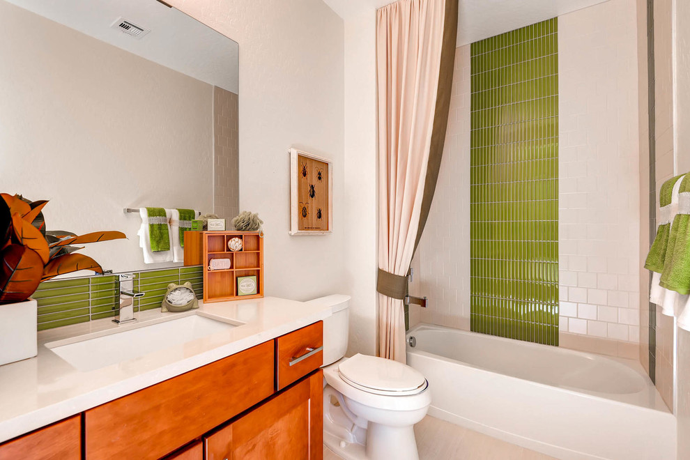 Photo of a mid-sized transitional bathroom in Las Vegas with shaker cabinets, medium wood cabinets, an alcove tub, an alcove shower, a one-piece toilet, beige tile, glass tile, beige walls, ceramic floors, an undermount sink, solid surface benchtops and a shower curtain.