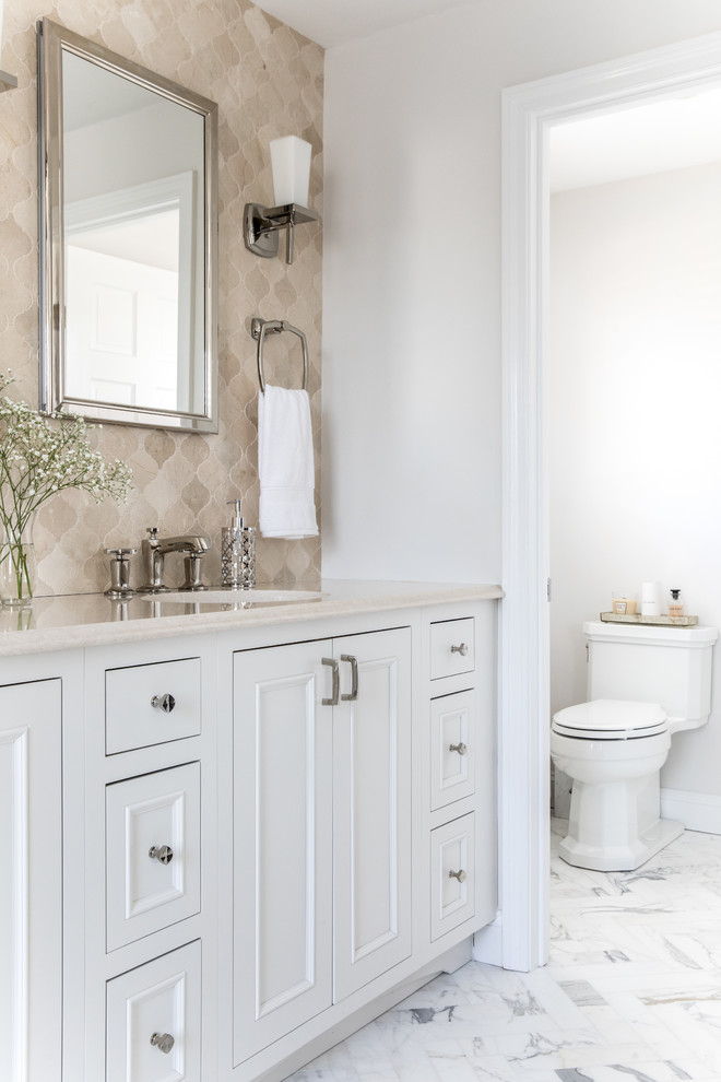 Transitional master beige tile and mosaic tile marble floor and gray floor freestanding bathtub photo in Boston with recessed-panel cabinets, white cabinets, a one-piece toilet, white walls, an undermount sink, quartz countertops, a hinged shower door and beige countertops