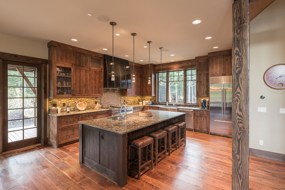Country l-shaped kitchen in Seattle with recessed-panel cabinets, medium wood cabinets, stainless steel appliances, medium hardwood floors, with island and brown floor.