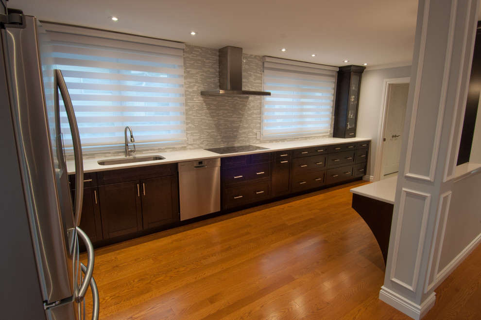Example of a large transitional galley light wood floor enclosed kitchen design in Toronto with a single-bowl sink, shaker cabinets, dark wood cabinets, quartzite countertops, beige backsplash, stone tile backsplash, stainless steel appliances and an island