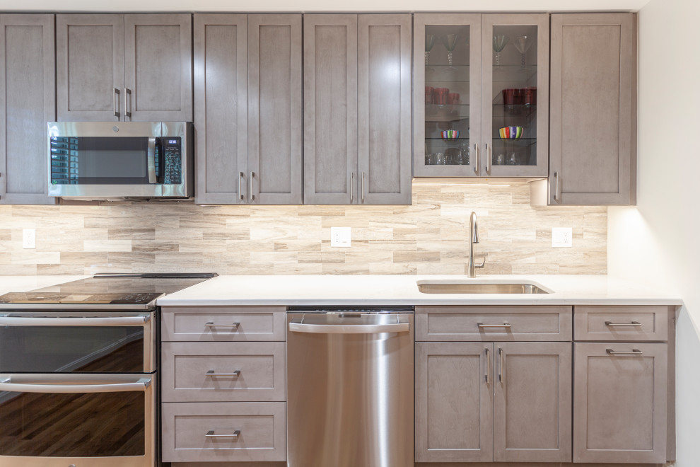 Photo of a medium sized traditional l-shaped enclosed kitchen in DC Metro with a submerged sink, shaker cabinets, grey cabinets, engineered stone countertops, multi-coloured splashback, marble splashback, stainless steel appliances, medium hardwood flooring, no island, brown floors and beige worktops.