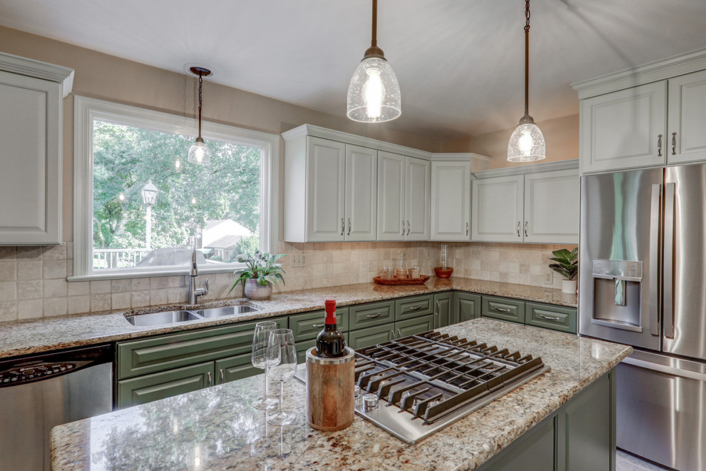 Example of a mid-sized transitional l-shaped ceramic tile and beige floor eat-in kitchen design with a double-bowl sink, raised-panel cabinets, green cabinets, granite countertops, beige backsplash, ceramic backsplash, stainless steel appliances, an island and beige countertops